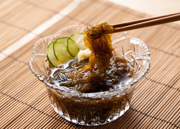 薬味(きゅうり・生姜)を添えたもずく酢 お箸ですくう様子