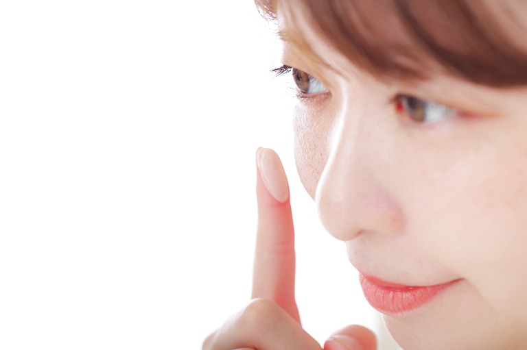 肌に下地やファンデーションを指で塗る女性　美容イメージ