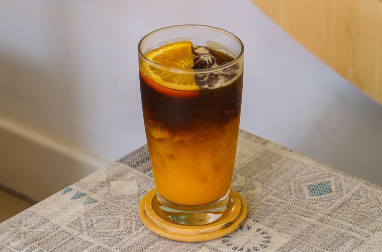 シトラスフルーツコーヒーイメージ　オレンジゼリーの層の上にコーヒー、その上にカットオレンジを乗せたドリンク