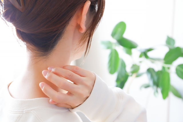 首の後ろに手を当てる女性の後ろ姿