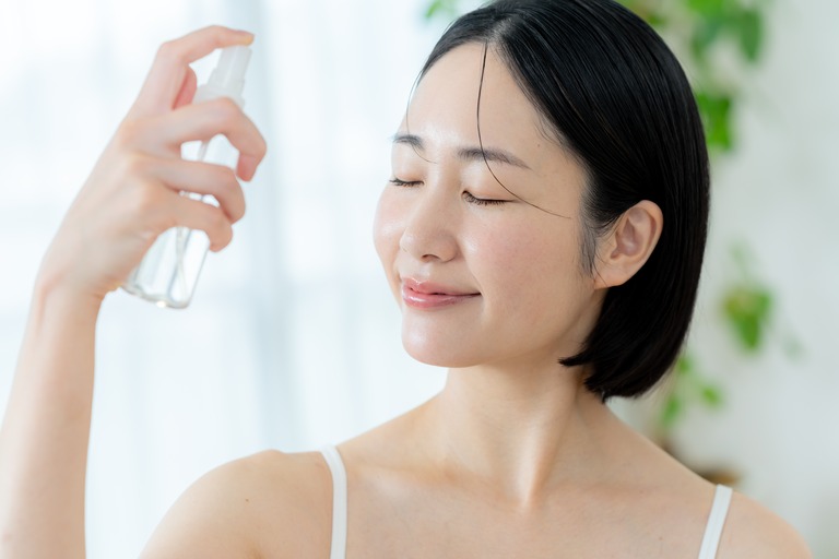 顔にミスト・スプレーをかける女性