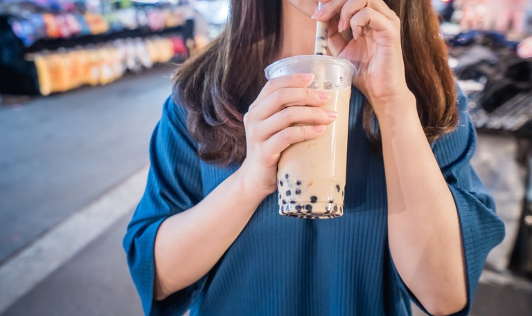街中で大きなタピオカドリンクを飲む女性 デカドリンク