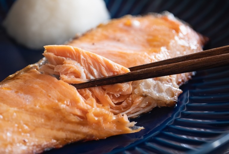 グリルで焼いた鮭の切り身。箸でほぐして食べるところ