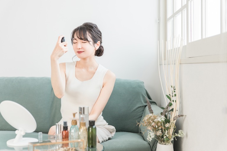 顔にミスト・スプレーをかける女性