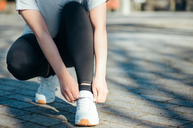 これからランニングをする女性イメージ　シューズの靴紐を結ぶ