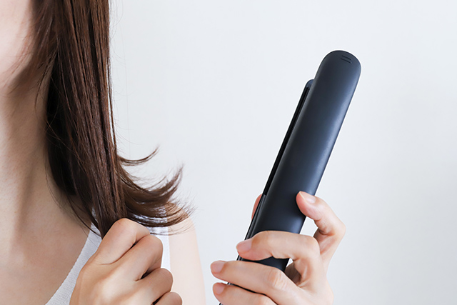 ヘアアイロンを使う女性