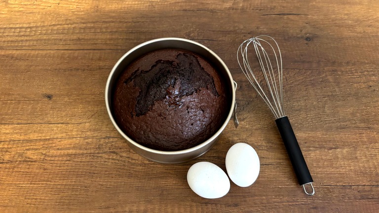 丸い型に入れて焼いたチョコレートのケーキと、卵と泡立て器